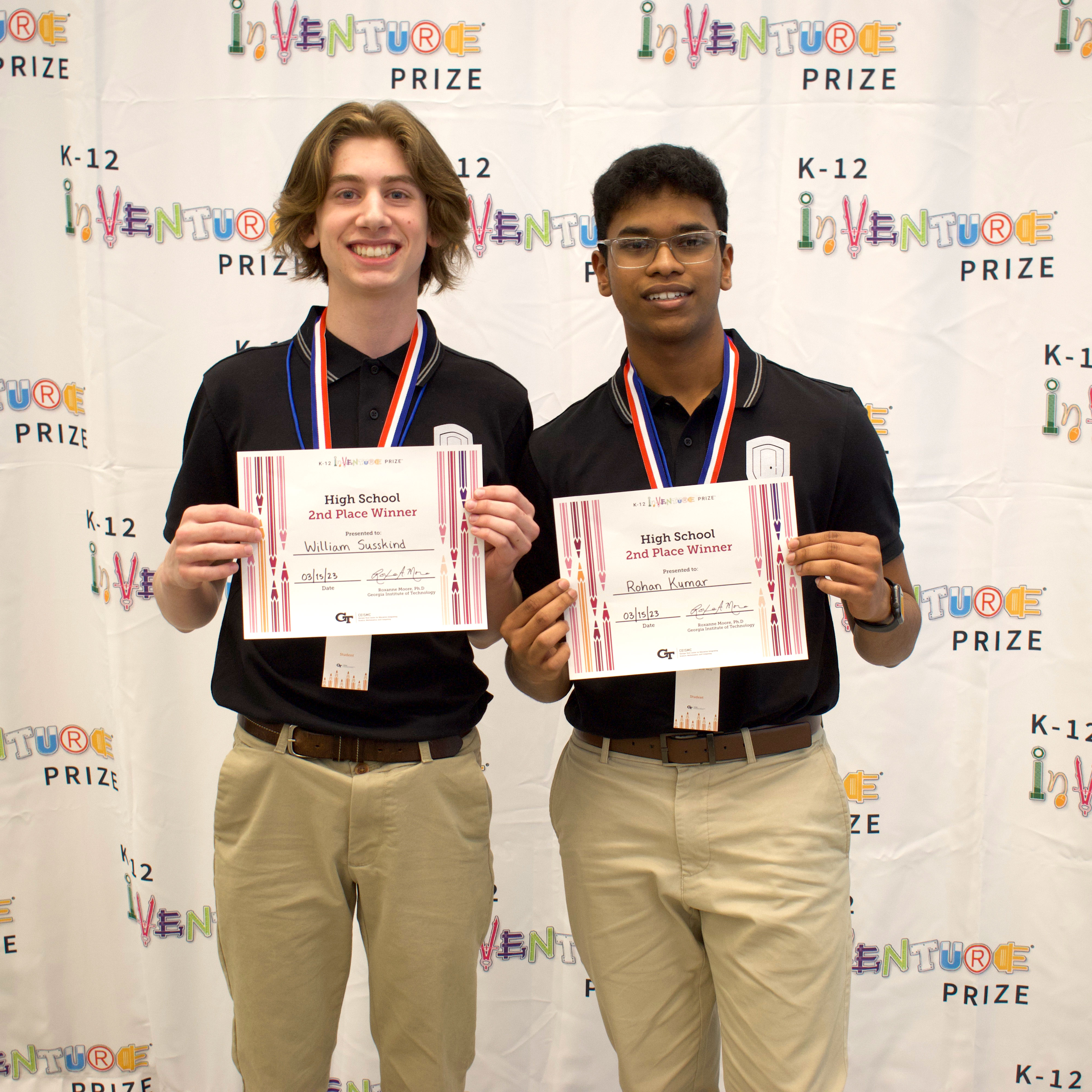 Two smiling students holding up certificates