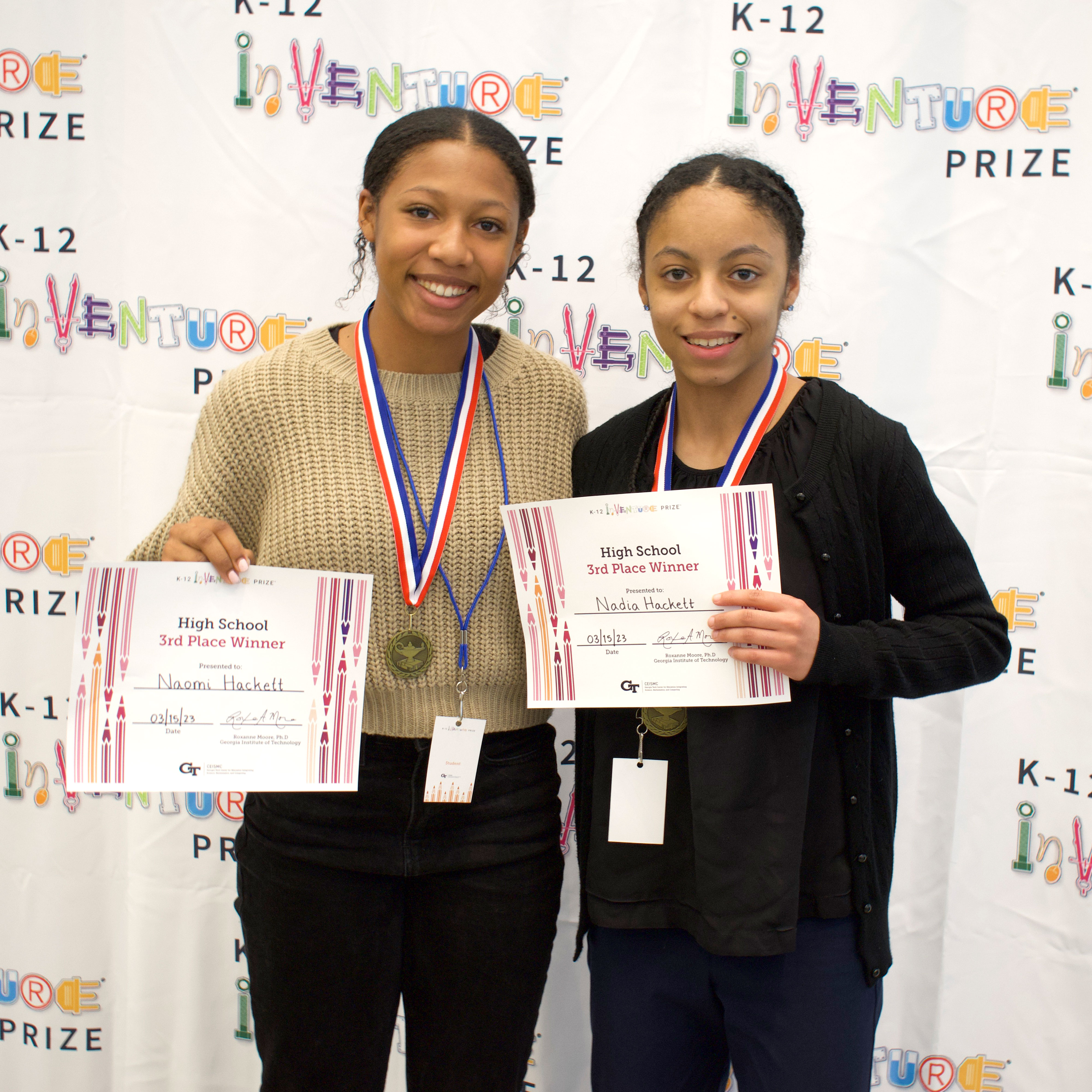 Two smiling students holding certificates