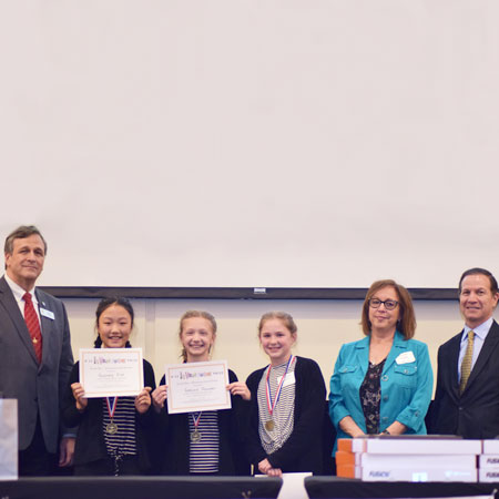 Three smiling students holding up certificates and standing beside three smiling adults