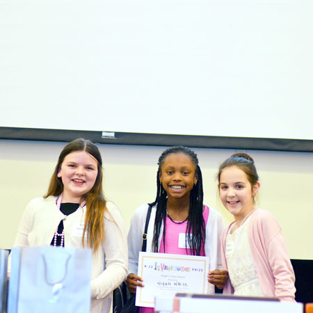 Three smiling students with one student holding up a certificate