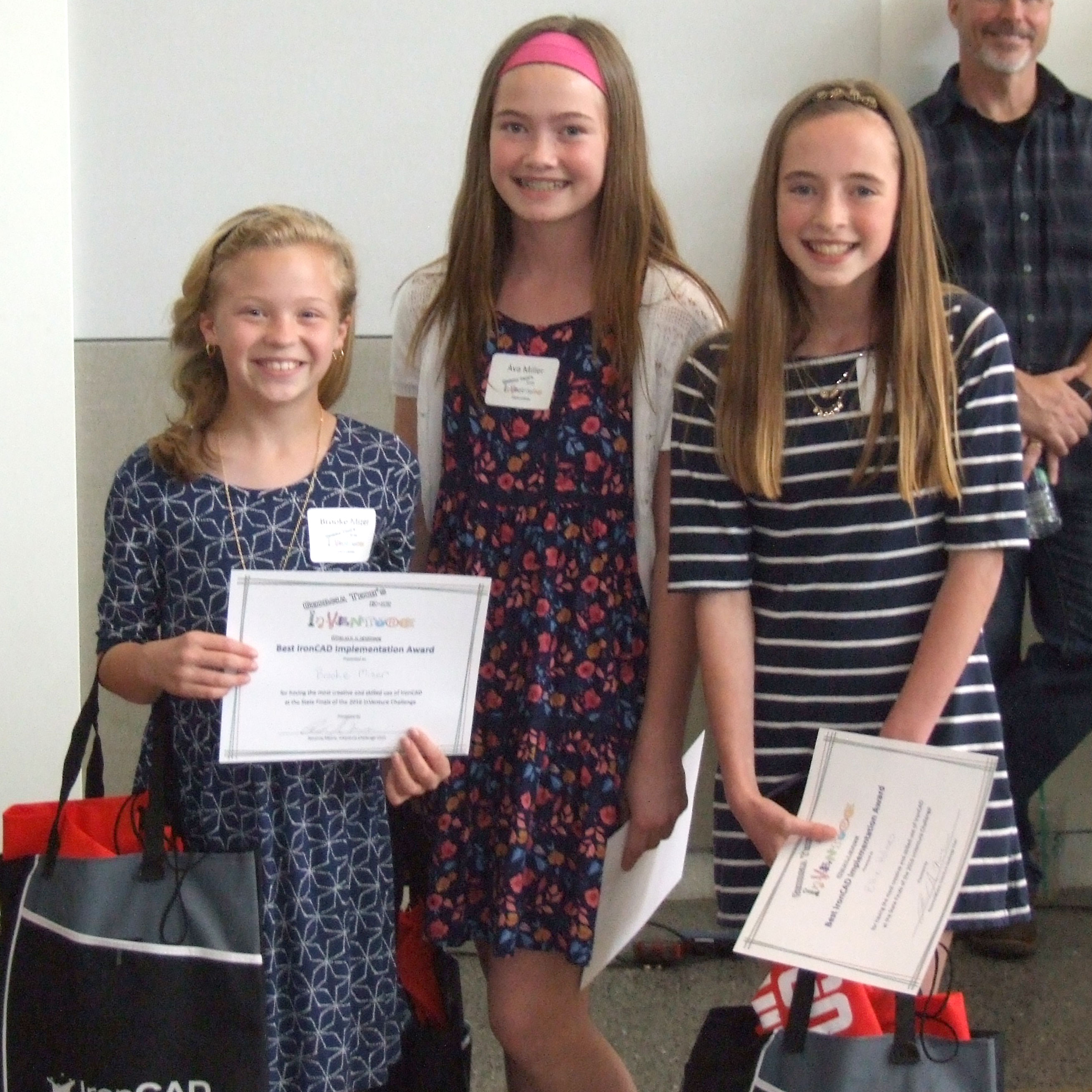 Three smiling students holding certificates