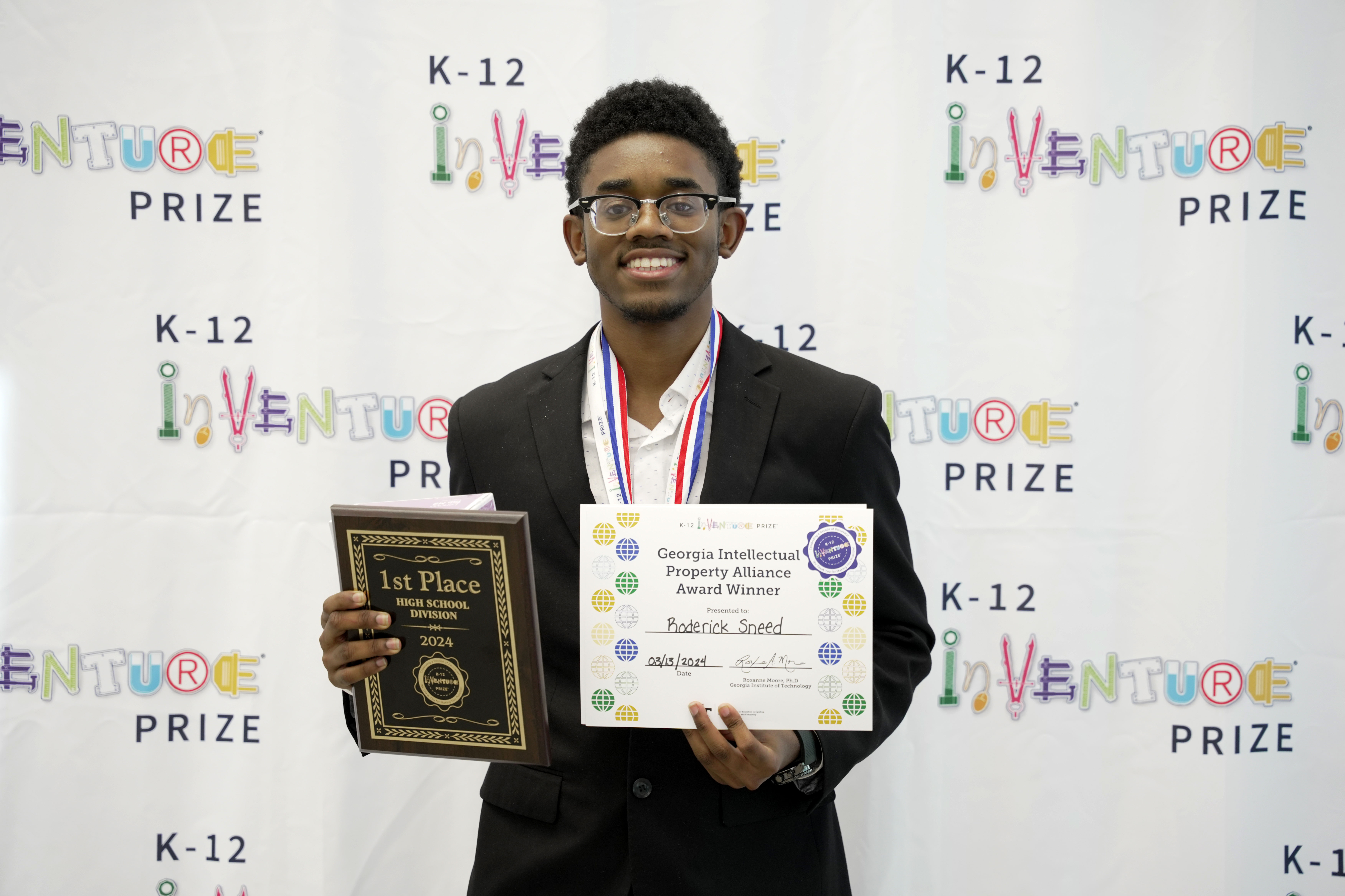 A smiling student holding a plaque and certificate