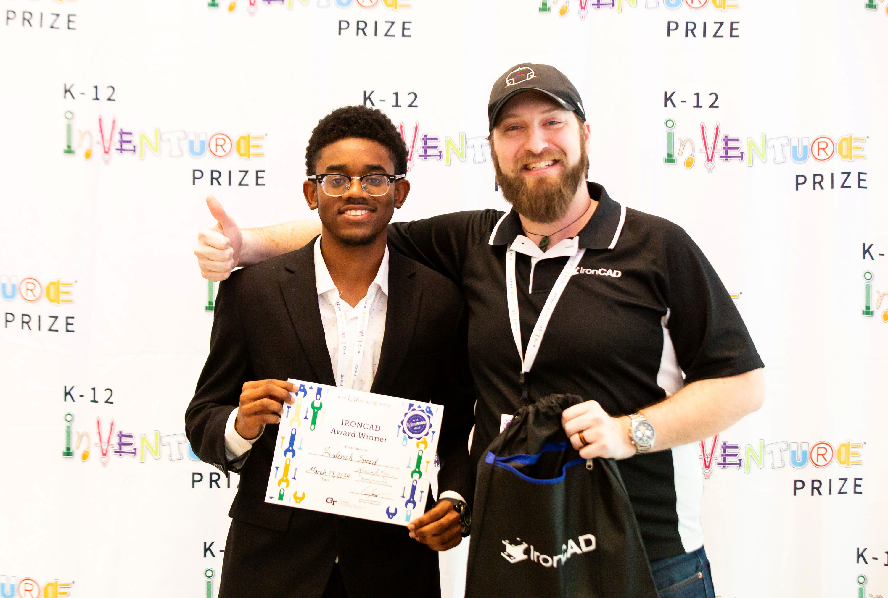 A smiling student holding a certificate next to a smiling IronCAD representative