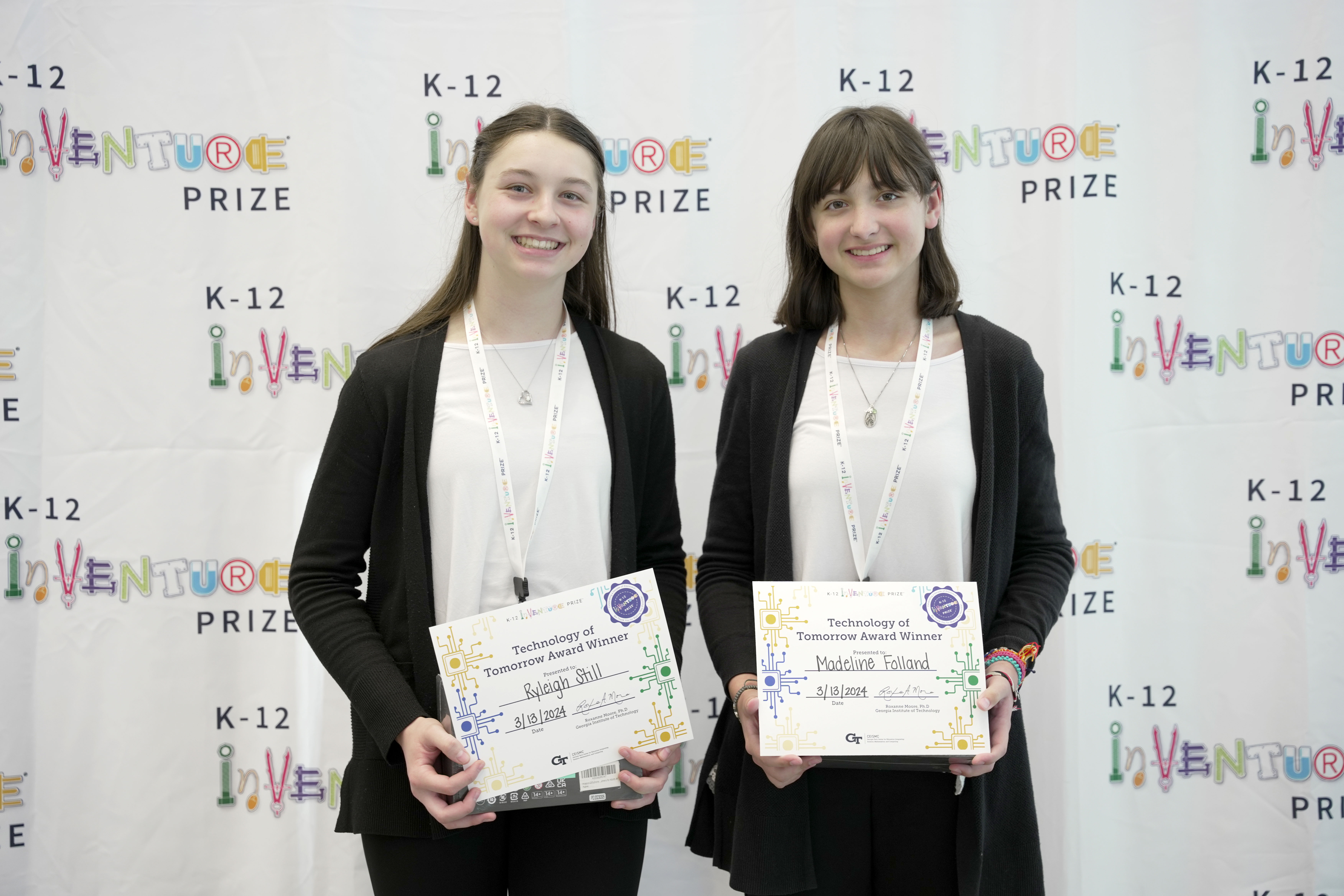 Two smiling students holding certificates