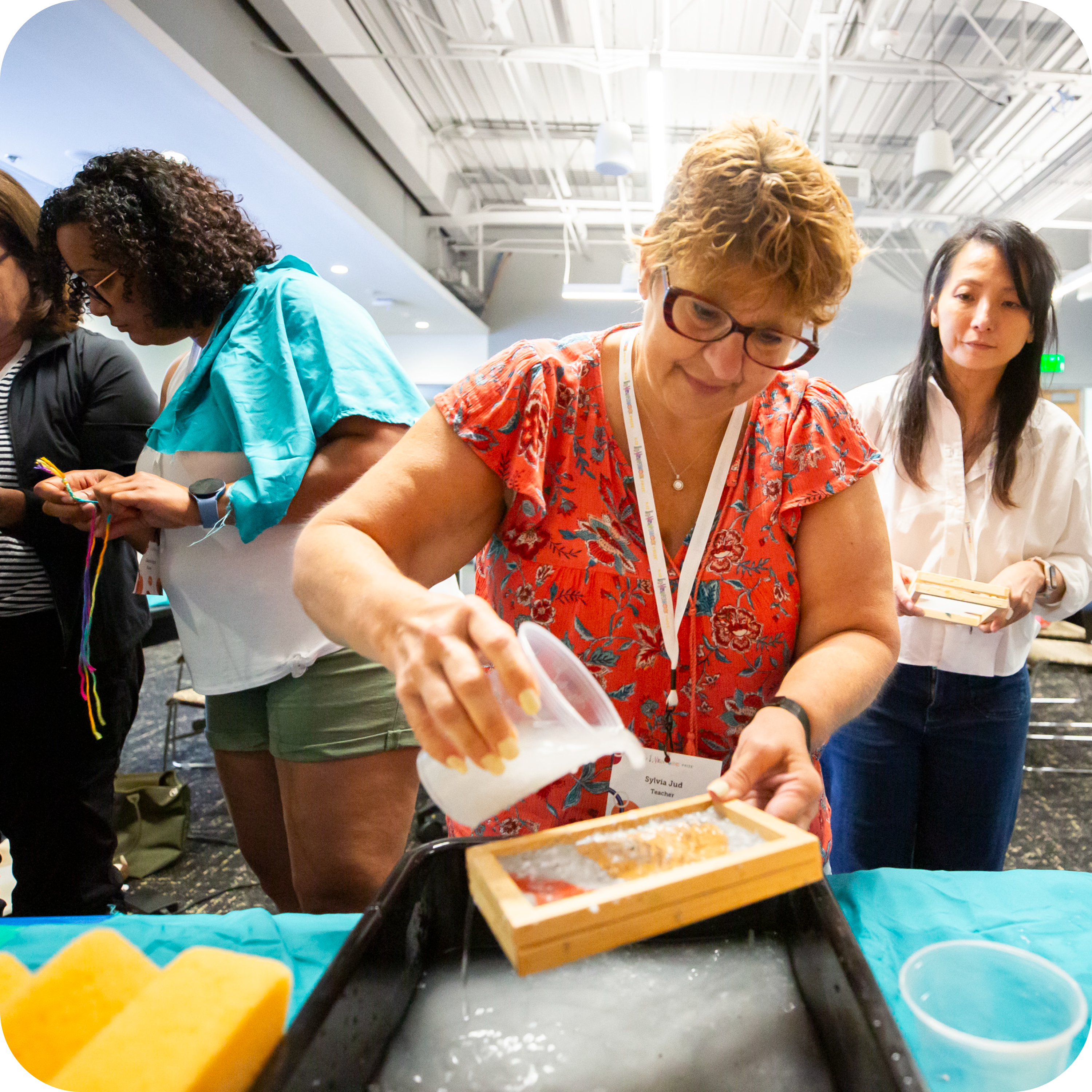 Teacher pouring paper mixture from container into paper mould