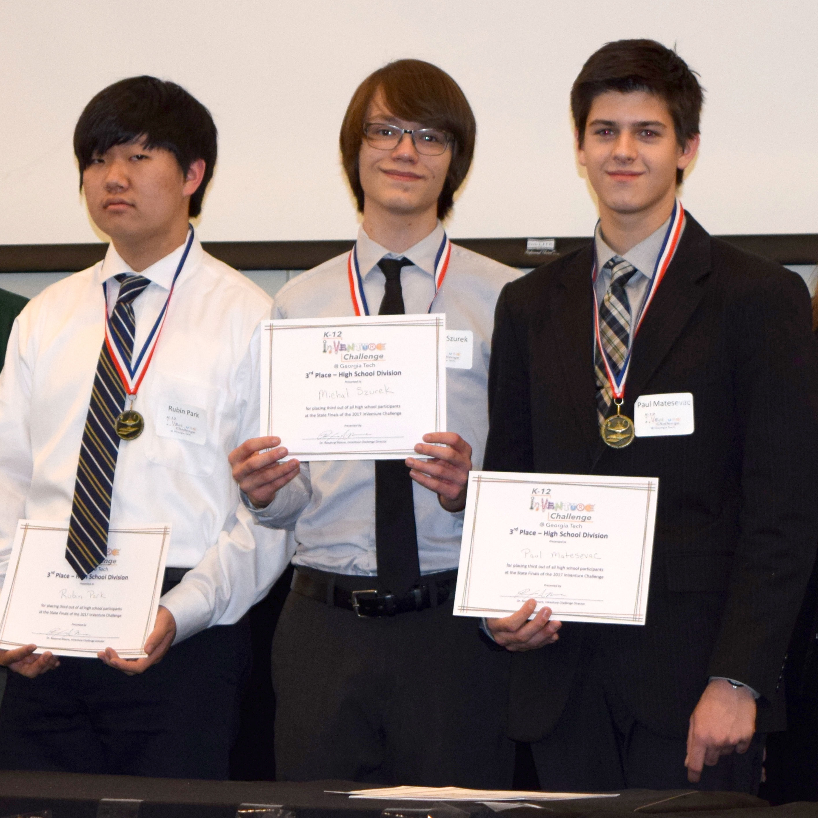 Three smiling students holding up certificates