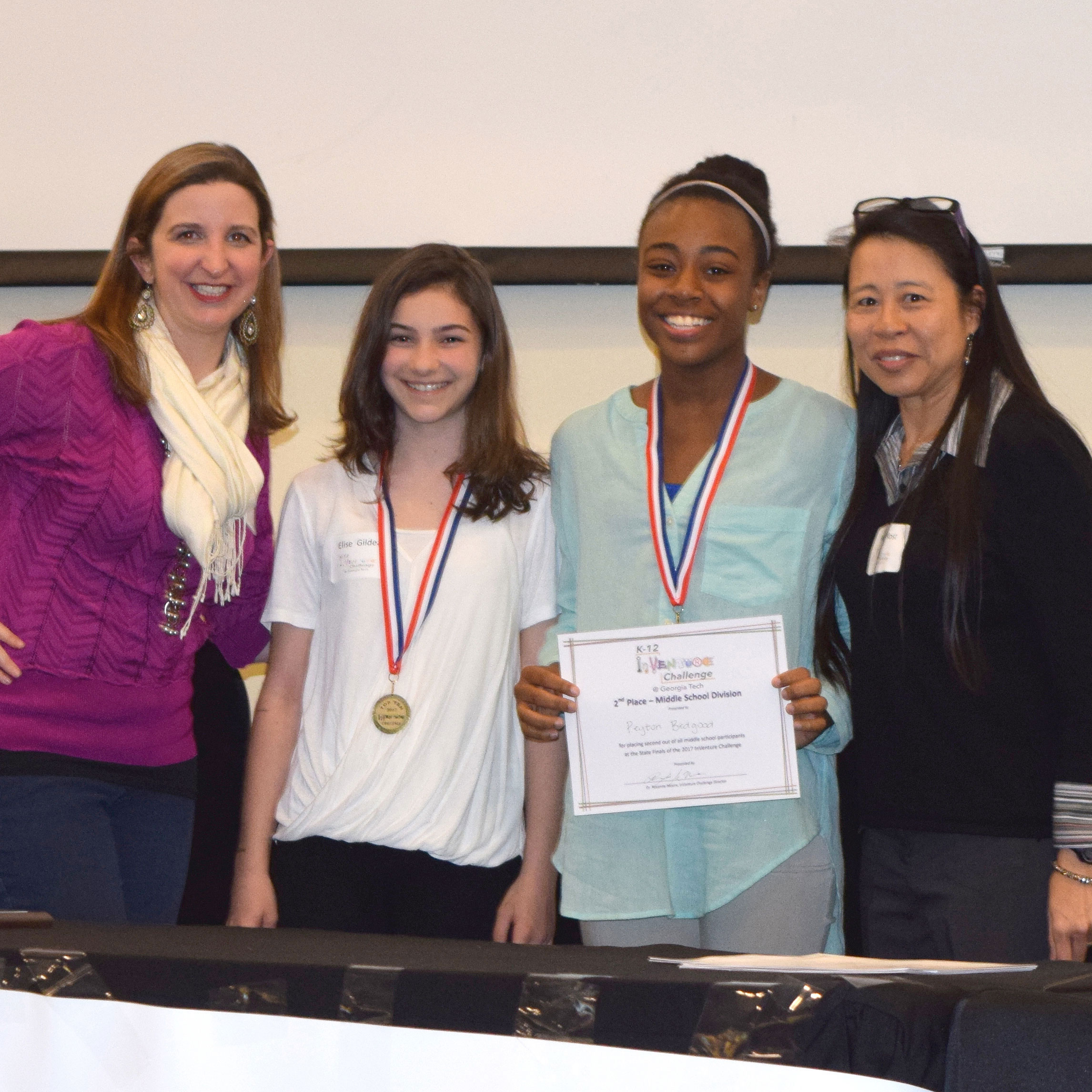 Two smiling students standing next to two smiling adults