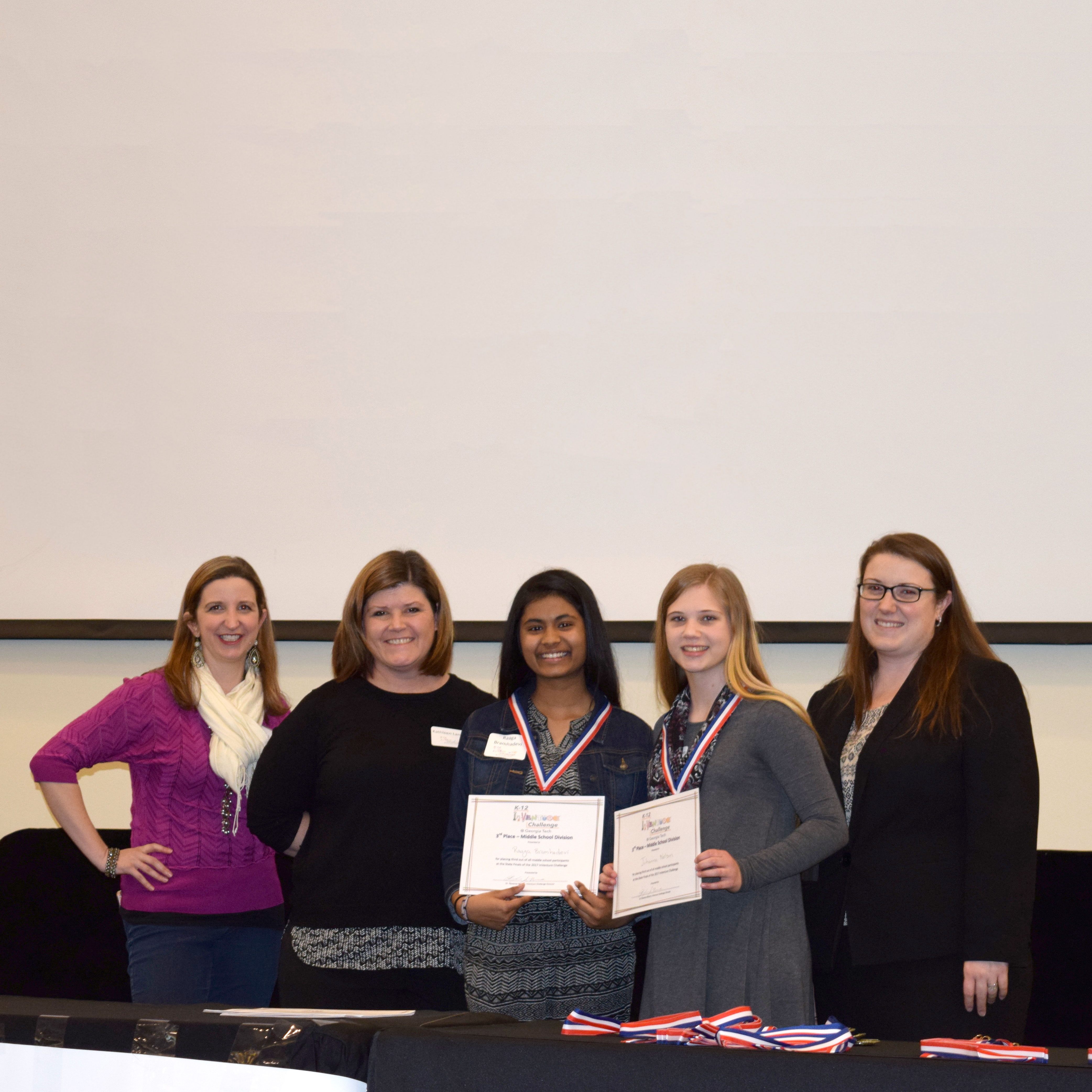 Two smiling students standing next to two smiling adults